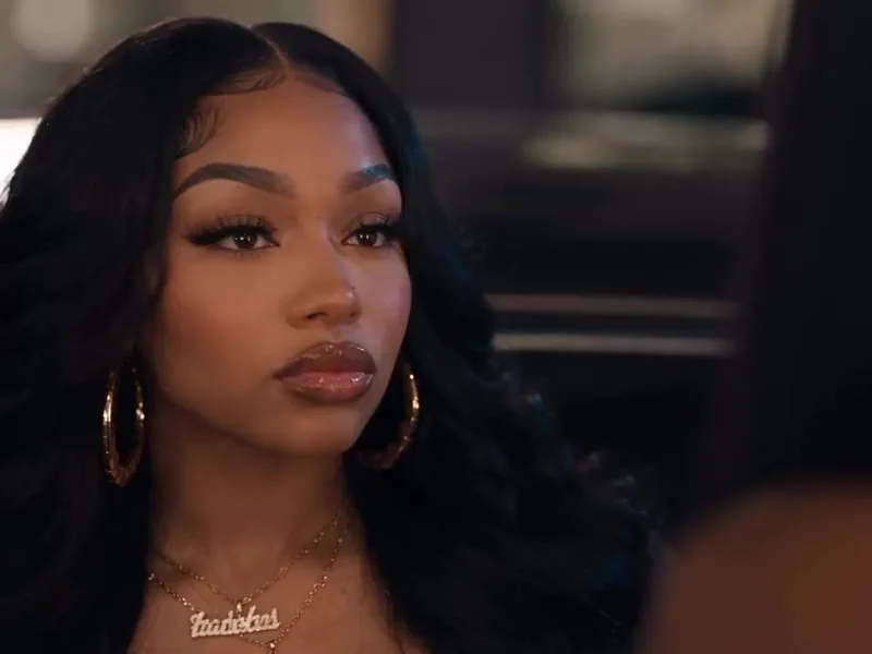 Close-up of a woman with hoop earrings and a gold name necklace